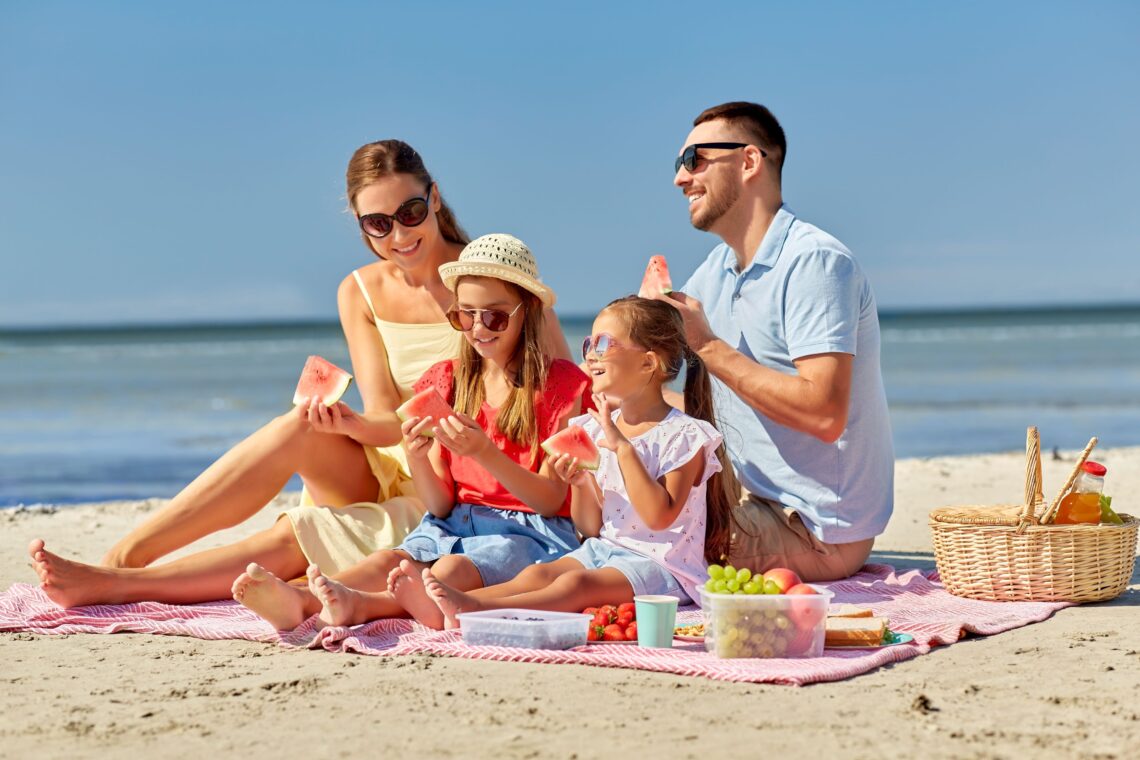 Familia disfrutando de un trozo de sandía en la playa