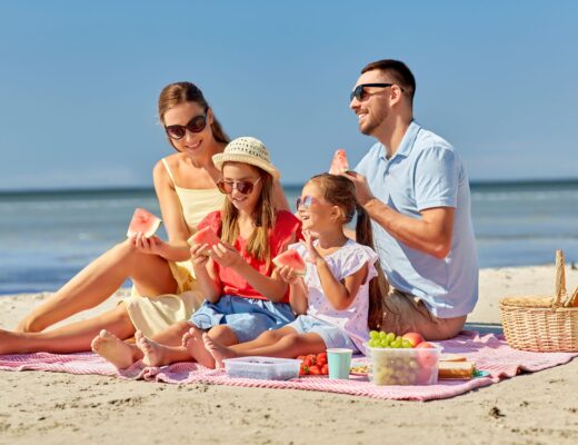 Familia disfrutando de un trozo de sandía en la playa