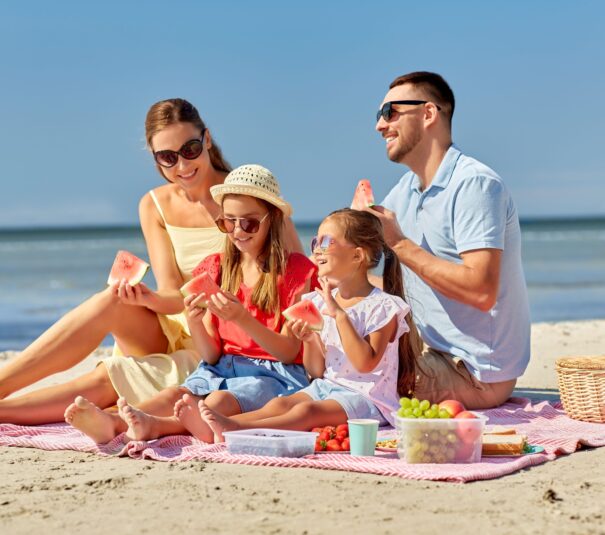 Familia disfrutando de un trozo de sandía en la playa