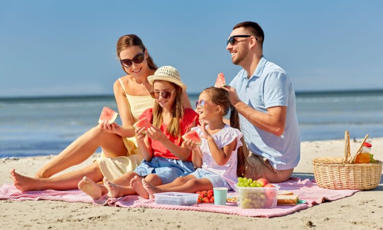 Familia disfrutando de un trozo de sandía en la playa