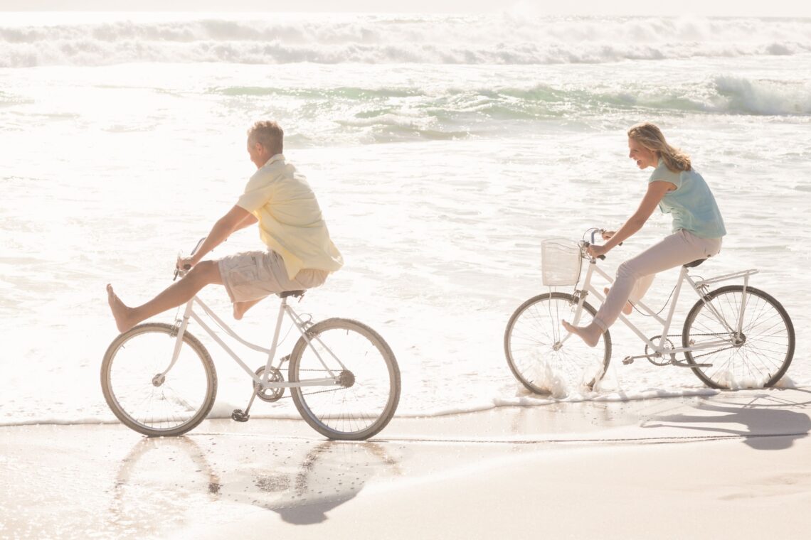 Pareja feliz dando un paseo en bicicleta por la orilla de la playa