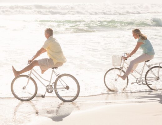 Pareja feliz dando un paseo en bicicleta por la orilla de la playa