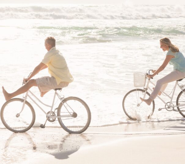 Pareja feliz dando un paseo en bicicleta por la orilla de la playa