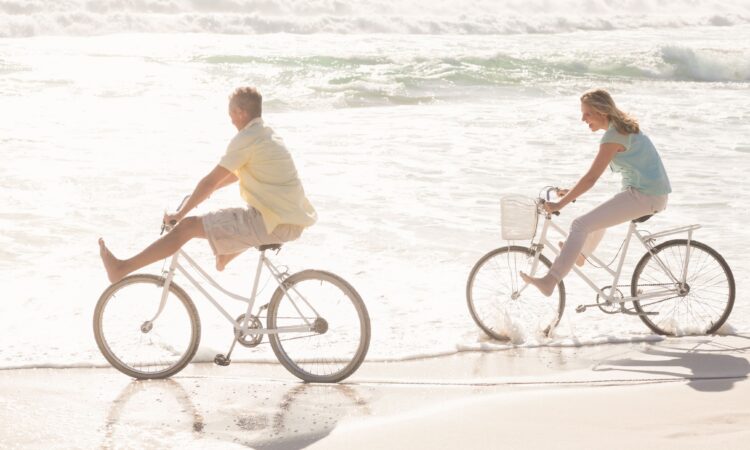 Pareja feliz dando un paseo en bicicleta por la orilla de la playa