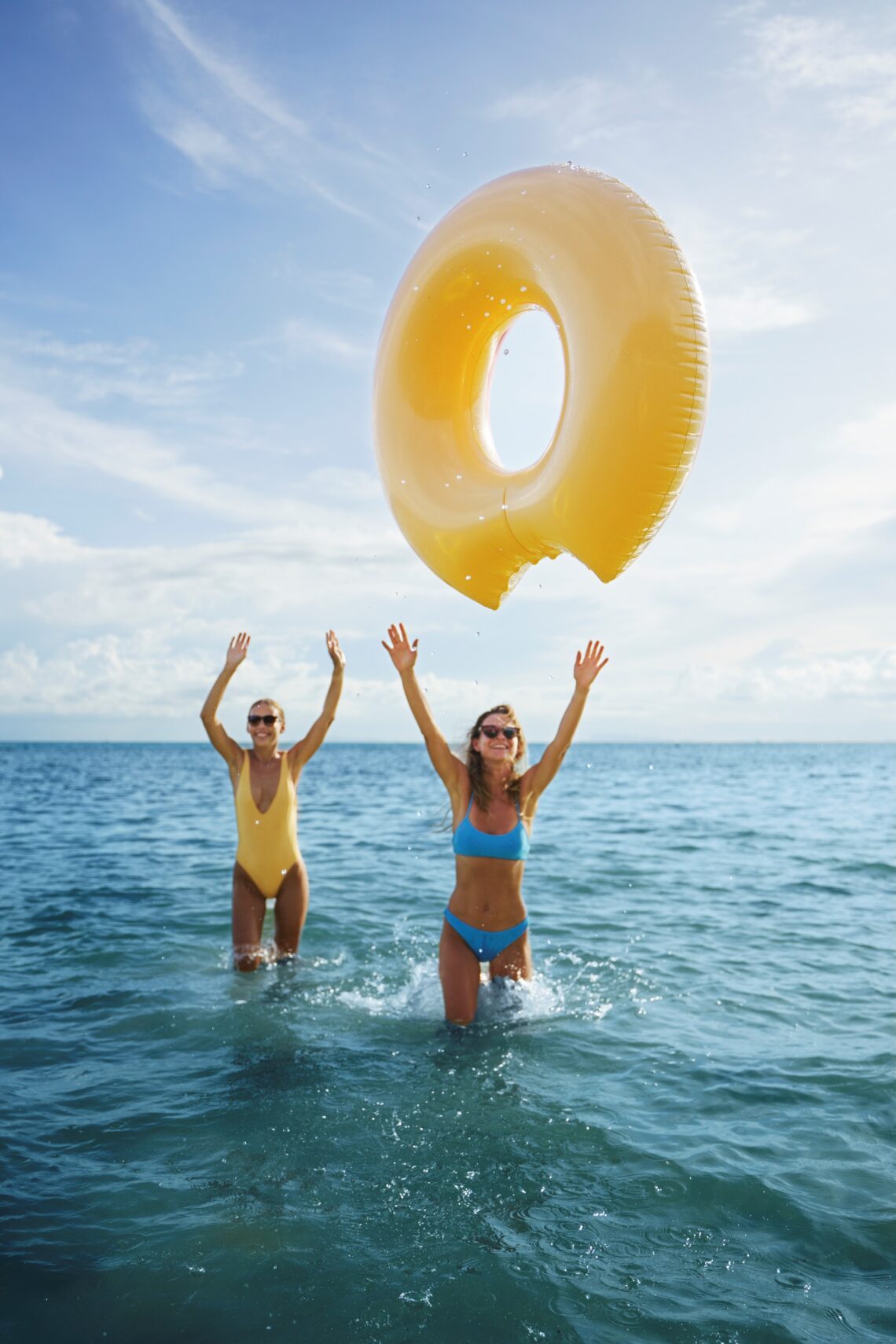 Dos mujeres jovenes jugando con una dona y disfutando del mar el sol y la brisa marina