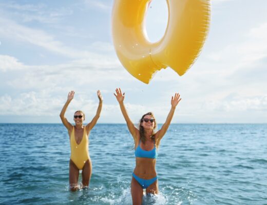 Dos mujeres jovenes jugando con una dona y disfutando del mar el sol y la brisa marina