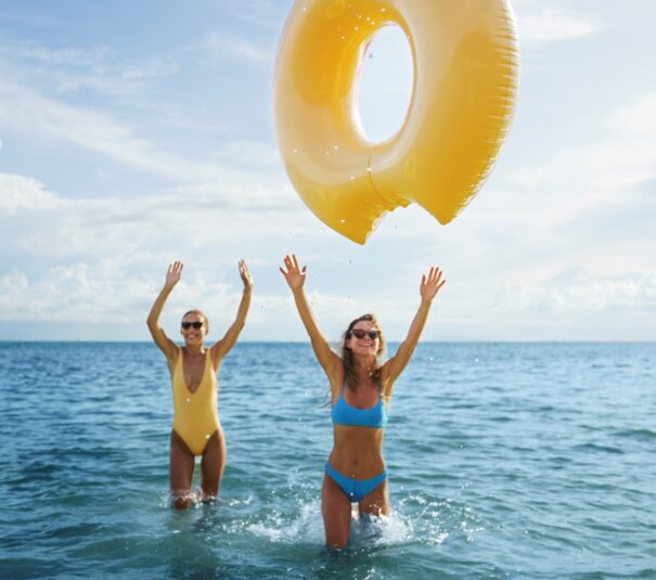 Dos mujeres jovenes jugando con una dona y disfutando del mar el sol y la brisa marina