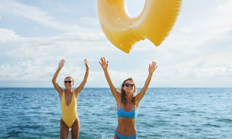 Dos mujeres jovenes jugando con una dona y disfutando del mar el sol y la brisa marina