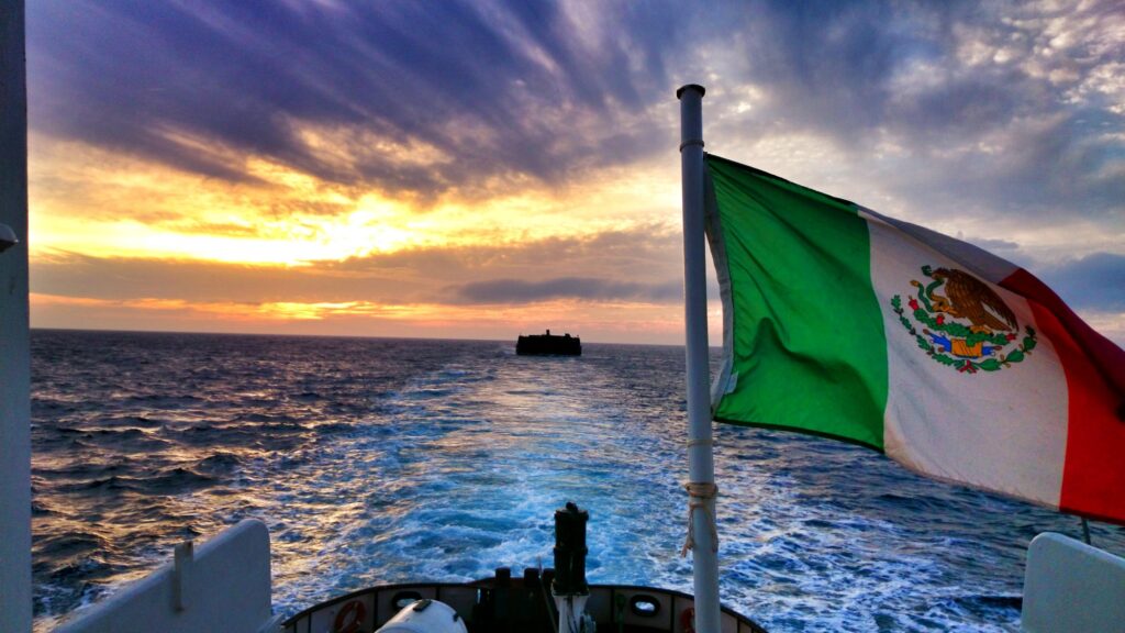 Bandera de México ondeando sobre el mástil de una embarcación en medio del mar