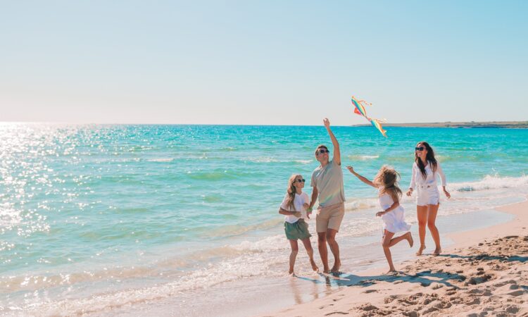 Familia feliz disfrutando la playa volando un papalote