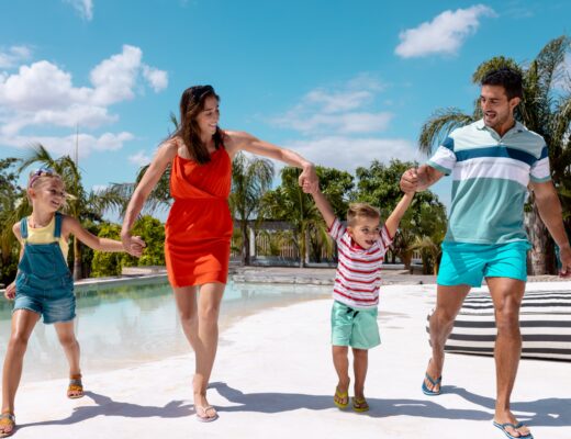 Feliz familia caminando y tomados de la mano junto a la piscina