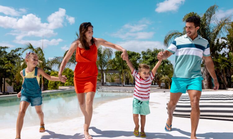Feliz familia caminando y tomados de la mano junto a la piscina