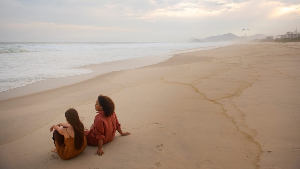 Mujeres hermosas sentadas en la arena de la playa disfrutando del clima cálido que se presenta en el otoño