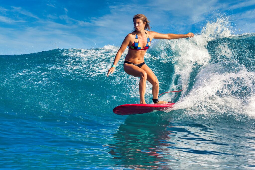 Surfista femenina en una ola azul en un día soleado de otoño