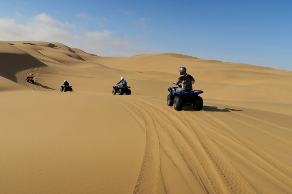 grupo de amigos paseando en cuatrimotos en las dunas de la playa