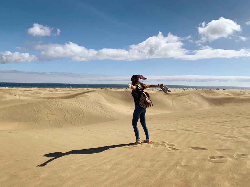 mujer-con-los-brazos-extendidos-de-pie-en-las-dunas-de-la-playa-disfrutando-de-la-sensación-que-produce-estar-en-contacto-con-la-naturaleza